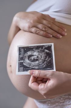 Pregnant woman holding a scan photograph against her bump