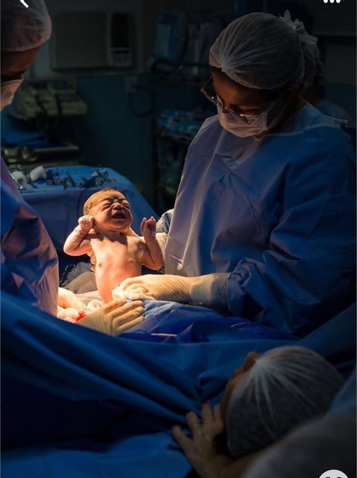 Newborn baby held by the doctor moments after delivery